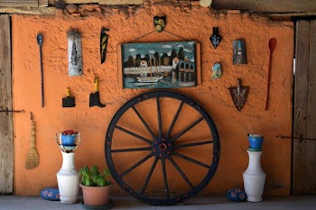 Black Wooden Carriage Wheel Leaning on Orange Painted Wall
