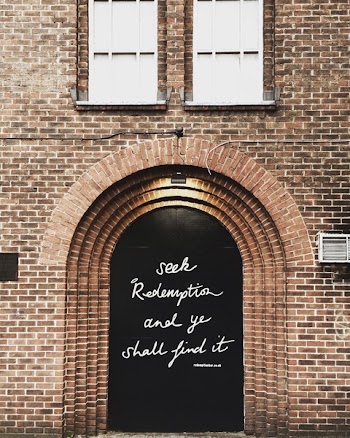 Black Wooden Door With Quote Printed at Daytime