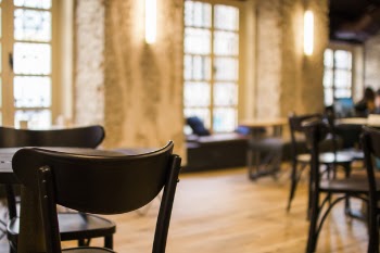 Black Wooden Tables and Chairs Arranged Inside Restaurant With Yellow Sconce