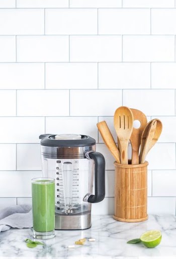 blender pitcher beside glass cup filled with green liquid