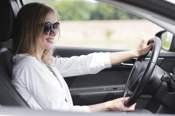 Blonde woman driving a car while wearing glasses Free Photo