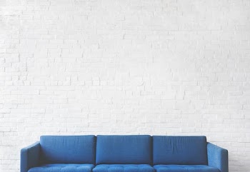 blue 3-seat sofa near white brick wall