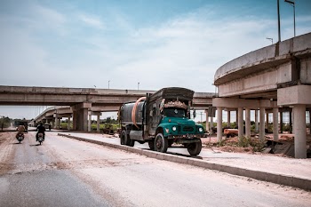 Blue and Black Truck on Road Near Building and Two Motorcycles