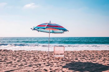 blue and red parasol and white chair at seashore