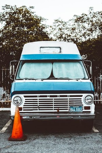 blue and white Ford car beside orange traffic cone