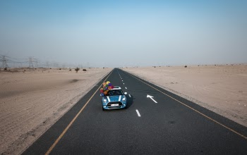 Blue and White Mini Cooper With Balloons Running on Road