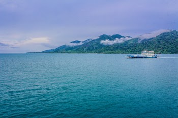 Blue and White Yacht on Teal Sea Near Green Mountain
