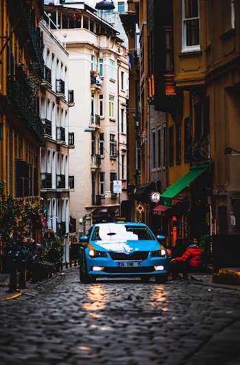 Blue Car on Road Between Buildings