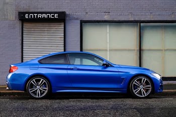 blue coupe beside gray house