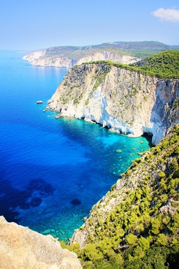 Blue Deep Body of Water Near Cliff With Green Trees Under Blue Sky
