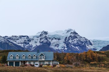 blue house beside trees near snow covered mountain