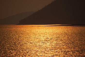 Blue Sea Near Brown Mountain during Sunset