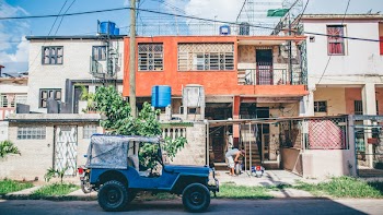 Blue Vehicle Parked on Road on Front of Orange House