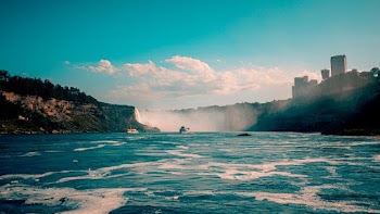 Boats In Calm Waters Near Rock Formation And Waterfalls
