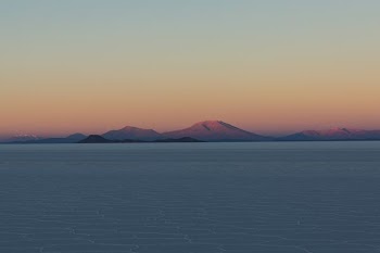 body of water and brown mountains under orange skies during sunset