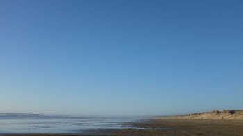 body of water and gray seashore under blue sky