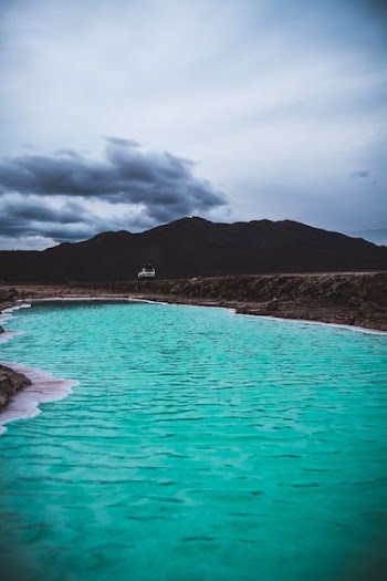 body of water beside brown mountain