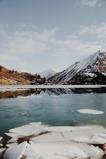 body of water beside mountain covered with snow
