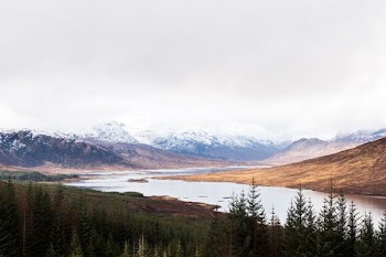 body of water between mountains under cloudy sky