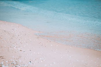 body of water crashing on brown sand