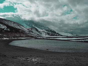 Body of Water in Front of Snow Covered Mountains