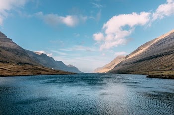 body of water in the middle of brown mountains under clear blue sky