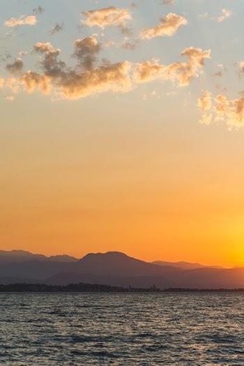 body of water infront of mountain during sunset