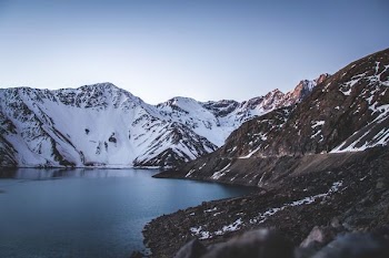 body of water near mountain covered with snow