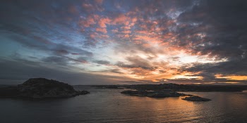 Body of Water Near Mountains Taken Under Orange Clouds during Sunset