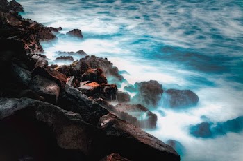 body of water smashing trough rocks