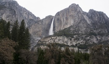 Body of Water Surrounded by Brown Moutains Under White Sky during Daytime
