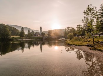 body of water surrounded by green trees near white tower under gray sky at golden hour