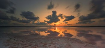 body of water under white sky at golden hour