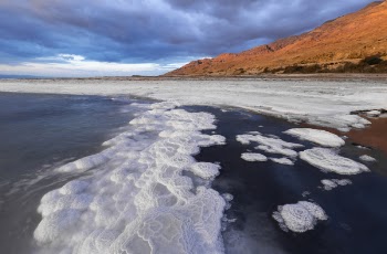 Body of Water With Bubbles Near Mountain
