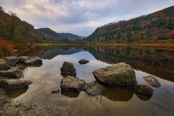 Body of Water With Rock Under White Sky