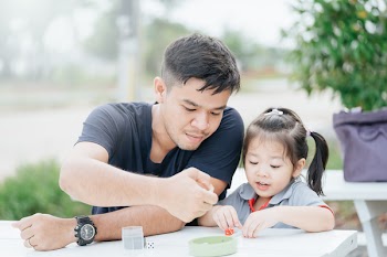 bonding time! Father and his child are playing at home.Cute little asian girl play math game with her dad, sitting on the table outdoor at backyard garden.Family holiday and togetherness.