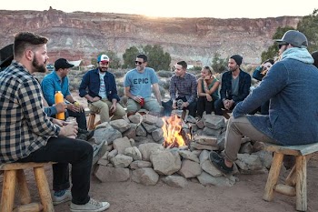bonfire surrounded by group of people near brown hill during daytime