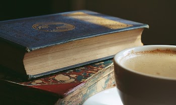 Book Beside Cup Filled With Brown Liquid