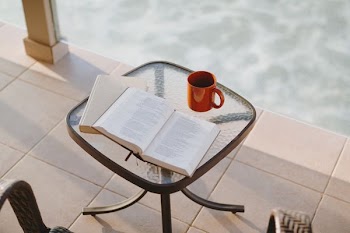 book beside mug on square clear glass-top table