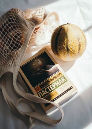 Book near fresh melon and string bag · Free Stock Photo