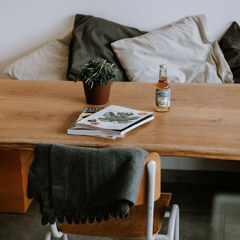 books on table near bottle and leaf plant in pot