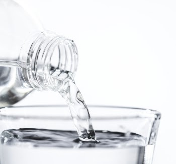 Bottle Pouring Water on Glass