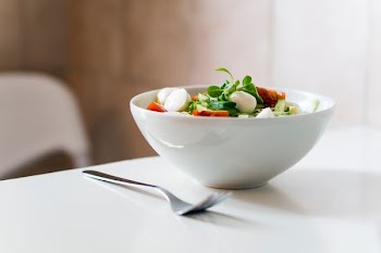 bowl of vegetable beside fork place on table