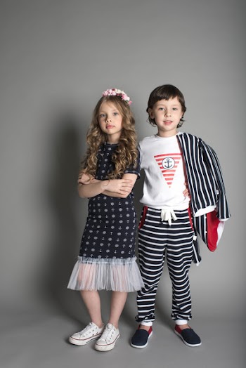 Boy and Girl Standing in Studio In Front of Grey Background