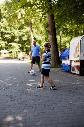 Boy and Man Playing Soccer on the pavement