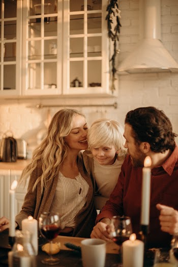 Boy Between Man and Woman Sitting Beside Table
