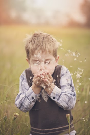 Boy Blowing Hands Filled With Dandelion Flowers