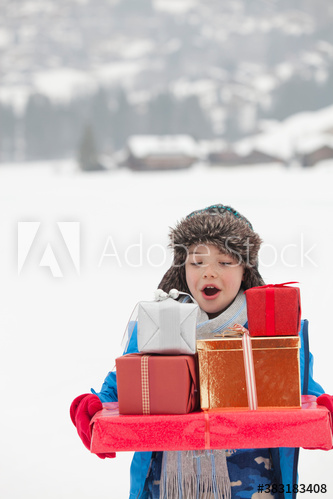 Boy carrying Christmas gifts in snowy field