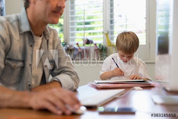 Boy coloring and father working in home office