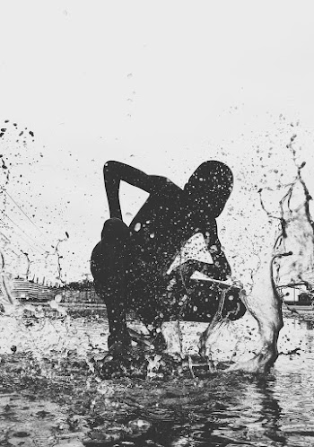 Boy Crouching on Puddle Of Water